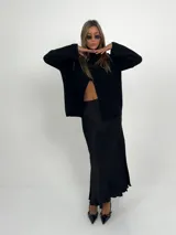 Falda midi negra de tela satinada, con cintura elástica y tajos laterales.