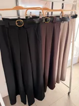 Pantalón de vestir color marrón chocolate, de corte ancho y tiro alto, con pinzas frontales y cinto negro con hebilla dorada incluido.