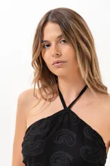 Vestido corto negro con escote halter y diseño cut out en los laterales de la cintura. Confeccionado en lino, cuenta con la parte superior en lino broderie con diseño paisley.