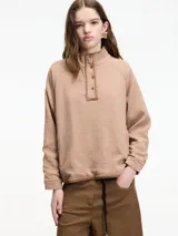 Sobrecamisa color beige, confeccionada en algodón texturizado (tipo guateado o nido de abeja), con cuello alto abotonado y mangas raglán.