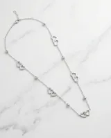 Collar largo de acero plateado con diseño de eslabones de cadena intercalados con pequeñas esferas y dijes de corazones entrelazados a lo largo de toda la pieza.