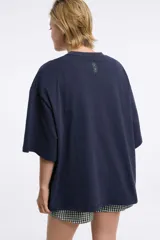 Remera blanca de corte boxy, cuello redondo a la base y mangas cortas. Presenta un pequeño estampado localizado en el centro del pecho que simula un ají en tono rojizo.