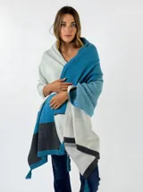 Pashmina tejida de lana con diseño de bloques de color en tonos gris claro, azul turquesa y gris oscuro, y flecos en los extremos.