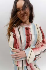 Chaqueta liviana de jean celeste con cuello mao, cierre frontal con alamares y detalle de bordados florales.