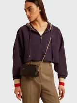 Cartera crossbody de cuero negro con diseño rectangular, cierre superior y correa de cadena dorada. Presenta el detalle de una estrella característica de la marca grabada en el frente.