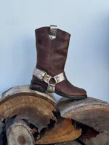 Bota de cuero marrón con estribo desmontable plateado.