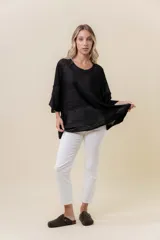 Buzo de tejido liviano negro con brillo sutil tipo lurex, cuello redondo, calce suelto y mangas amplias.