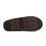 Pantufla tipo mule de cuero gamuzado color marrón, con interior de peluche y detalle de costura decorativa trenzada en el borde superior. Cuenta con una suela de plataforma dentada de goma.