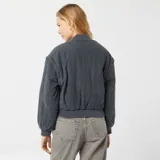 Campera bomber azul petróleo acolchada con cuello redondo, cierre con botones a presión, bolsillos con solapa y puños y cintura elásticos.