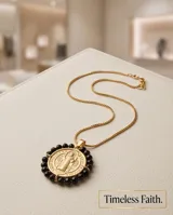 Collar de acero con baño de oro, con cadena fina y medalla colgante de San Benito rodeada por cristales negros facetados.