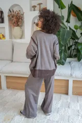 Pantalón gris de algodón con efecto vintage, corte ancho, cintura elastizada con cordón ajustable y detalle de ojales metálicos en los laterales.