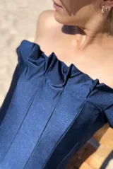 Malla enteriza strapless color azul marino, con diseño de escote con volados y costuras verticales que le dan una estructura tipo corset.