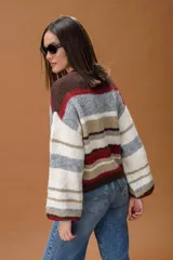Sweater de punto con diseño de rayas horizontales en tonos marrón chocolate, rojo, beige, gris y blanco. Presenta cuello redondo y mangas largas con puños ajustados.