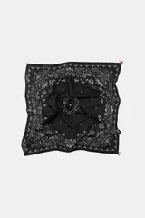 Pañuelo bandana de algodón negro con estampado paisley en blanco y detalles de abalorios y flores en crochet en las esquinas.