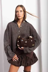 Cartera tipo baguette de gamuza color chocolate, con diseño decorado con diversos apliques metálicos, perlas y piezas de piedra. Cuenta con cierre superior y correa ajustable.