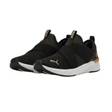 Championes Puma Softride Harli de color negro, con diseño slip-on sin cordones, tiras elásticas cruzadas en el empeine, detalles en tono dorado rosado con la marca en el lateral y el talón, y suela blanca amortiguada.