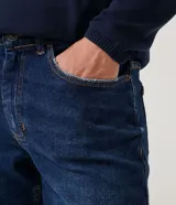 Pantalón de jean skinny azul oscuro con roturas en las rodillas y ruedo doblado.
