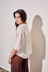 Blusa de lino y viscosa color blanco con estampado de lunares marrones, de manga corta y cuello camisero con cierre frontal de botones.
