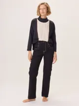 Remera blanca de manga larga con cuello alto, corte holgado y costuras verticales decorativas en el frente.