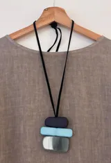 Collar largo con colgante de acrílico con forma de bloques rectangulares en color negro, celeste y gris.
