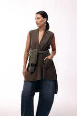 Chaleco de diseño fluido con escote cruzado y lazo ajustable en la cintura. Presenta un corte largo y versátil, ideal para superponer en diferentes looks.