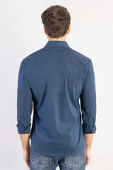 Camisa de manga larga color azul marino, con cuello clásico, cierre frontal de botones y corte recto. Presenta un diseño minimalista con logo bordado sutil en el pecho.