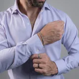 Camisa negra de algodón con cuello clásico, manga larga y cierre frontal con botones. Presenta un logo bordado en el pecho. Corte entallado.