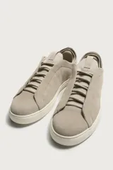 Zapatilla de piel con acabado en serraje de color gris, diseño de cordones ocultos y suela de goma en contraste de color blanco.
