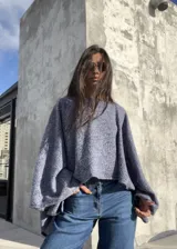 Poncho de hilo liviano en color azul jaspeado, con diseño sin cuello y caída fluida. Es una prenda versátil de talle único, ideal para usar como capa sobre otras prendas durante la media estación.