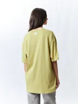 Remera negra de manga corta, corte oversize, con estampado frontal de una figura femenina de estilo asiático rodeada de flores blancas y verdes.