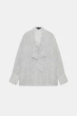 Camisa de viscosa con estampado de lunares pequeños, escote en pico con lazada frontal, manga larga y puños anchos.