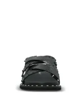 Sandalias negras de cuero con tiras cruzadas, tachas metálicas aplicadas y suela de EVA. Cuentan con tira ajustable en el talón con hebilla y ribete con tachas en la plataforma.
