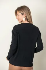 Sweater rojo de punto con cuello redondo, mangas largas, trenzado central y bolsillos delanteros.