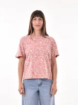 Remera rosa con estampado floral abstracto en blanco, de manga corta y cuello redondo.