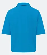 Camisa de manga corta confeccionada en mezcla de viscosa y lino color turquesa. Presenta cuello camisero con escote en V, bolsillos frontales de parche y cierre frontal con botones geométricos de efecto carey.