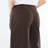 Pantalón de jean color marrón con corte globo, tiro alto y diseño de pierna ancha. Presenta costuras laterales marcadas y cierre frontal con botón y cremallera.
