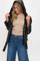 Chaqueta motera de cuero sintético color negro con capucha integrada. Presenta cierre frontal, cierres metálicos en los puños y cinturón ajustable en la cintura.