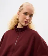 Campera de modal color marrón, con cuello alto, cierre frontal completo y diseño con pliegues en el ruedo. Presenta mangas largas y un calce holgado.