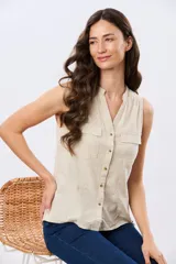 Musculosa de lino color beige, con cuello mao y escote en V, cierre frontal con botones y dos bolsillos plaqué con solapa en el pecho.