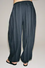 Pantalón bombacho Zara Woman Collection, confeccionado en mezcla de algodón, con tiro medio, cintura elástica y cordón ajustable. Presenta diseño a rayas sutiles, bajo abullonado con puño y cierre frontal con botón.