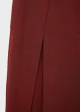 Pantalón de tiro medio color bordó, de diseño wide leg con pinzas delanteras y bolsillos laterales. Cuenta con cierre de cremallera, botón y ganchos ocultos con tapeta, además de forro interior.
