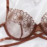 Conjunto de lencería de tul color chocolate con bordado floral, compuesto por un soutiene con aros y tiras cruzadas bajo el busto, y una bombacha colaless con tiras ajustables.