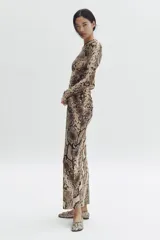 Vestido largo de malla de doble capa con estampado de piel de serpiente. Modelo entallado de manga larga, con escote redondo y detalle de costura fruncida lateral que crea un efecto drapeado.