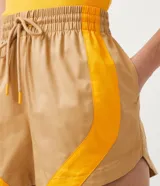 Short runner color beige con recortes laterales color naranja, cintura elástica con cordón ajustable y corte holgado.