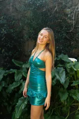 Vestido corto negro con escote en V, breteles finos cruzados en la espalda, abertura en la cintura y falda con volados.