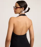 Vestido corto negro de malla punto roma, con escote halter y espalda descubierta. El ruedo es levemente evasé.