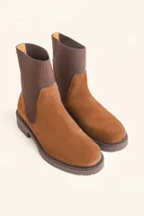 Bota tipo chelsea de gamuza color marrón, con paneles laterales elásticos acanalados y suela de goma track con taco bajo.