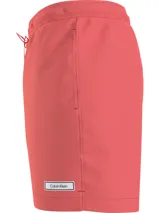 Bañador corto color salmón de poliéster reciclado, con cintura elástica ajustable con cordón, bolsillos laterales y trasero, forro de malla e insignia de goma con el logo de Calvin Klein en el bajo.