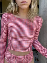 Top de lycra con estampado a cuadros rojos y blancos, de manga larga y corte ajustado.