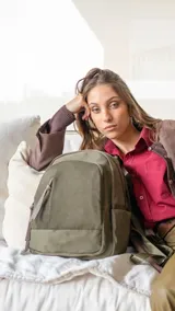 Mochila de diseño funcional confeccionada en tafeta, color verde oliva. Cuenta con compartimento principal con cierre, dos bolsillos frontales con cierres metálicos, bolsillos laterales y un bolsillo adicional en el dorso. Incluye correas regulables y tiradores de cierre en cuero sintético.